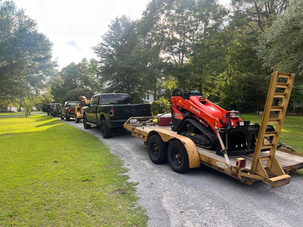 A kubota tractor is cutting down trees in a forest