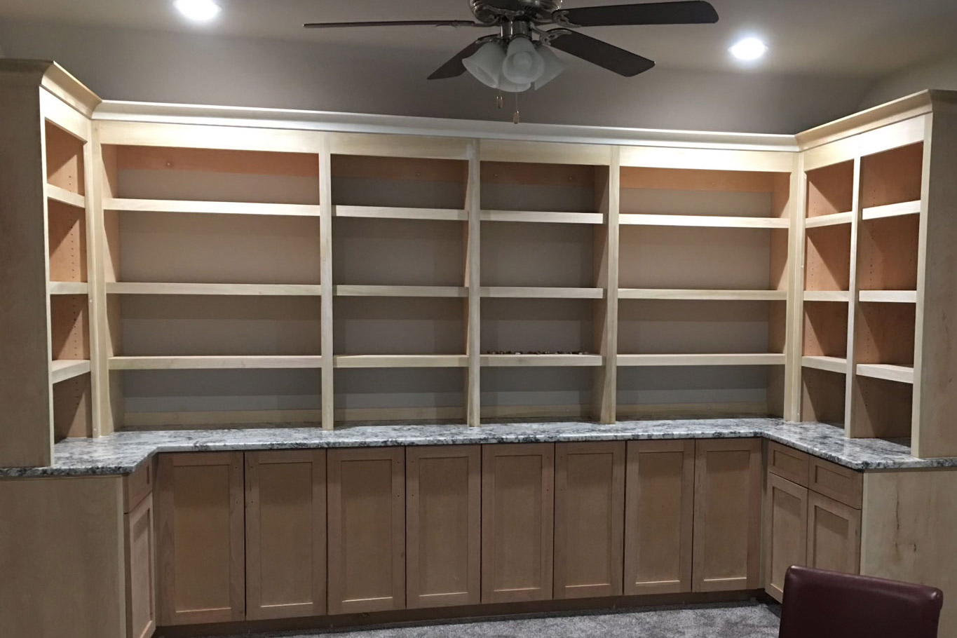A room with a lot of shelves and a ceiling fan.