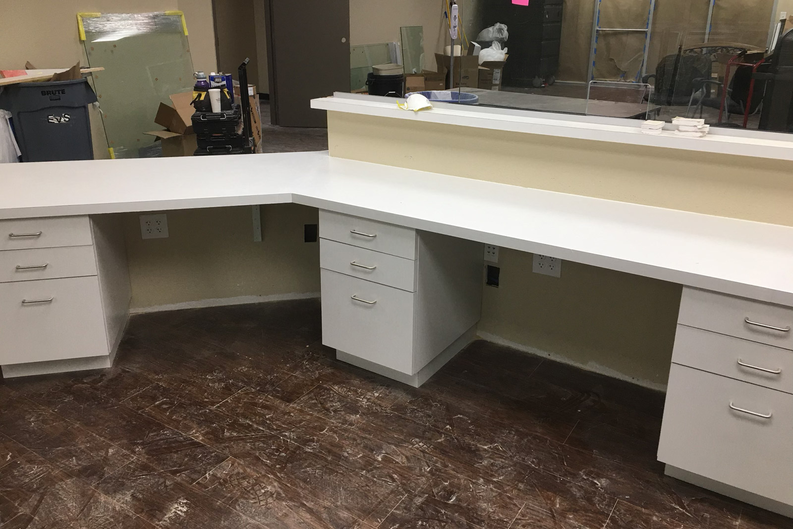 An empty office with a desk and drawers in it.