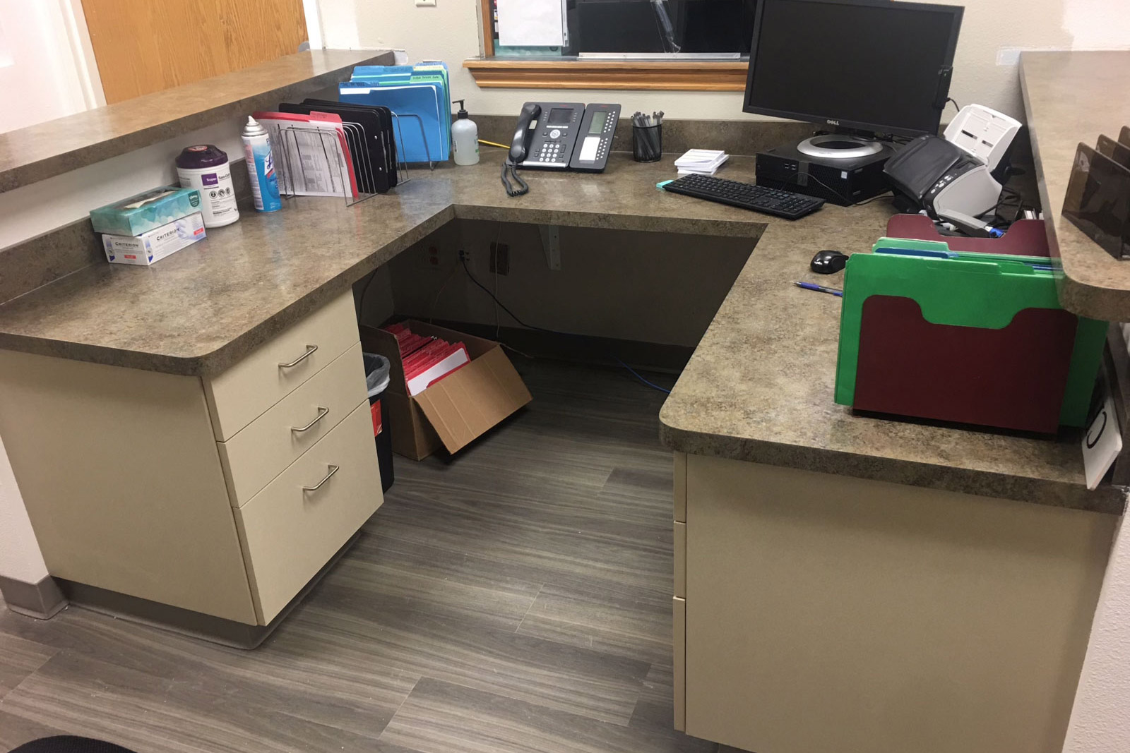 There is a desk with a computer and a phone on it.