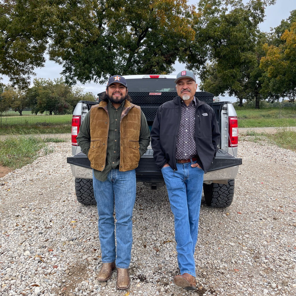 Two men are standing next to each other in front of a truck.