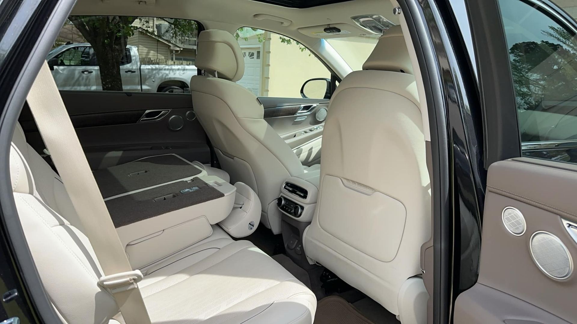 The back seat of a black car with white leather seats.