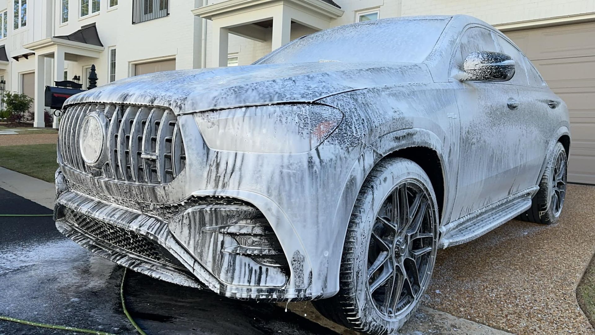 A car covered in foam is parked in front of a house.