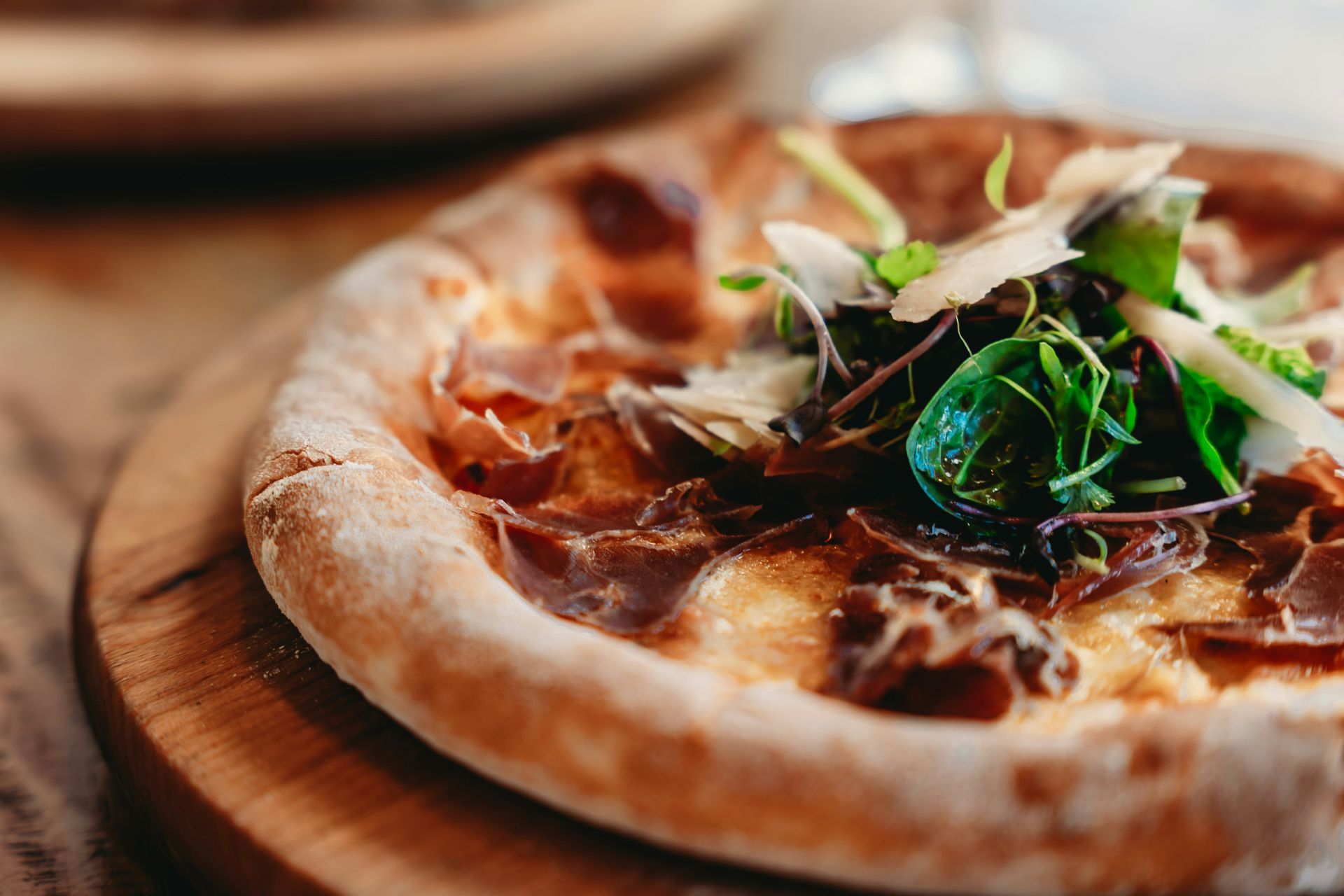 Close-up of a rustic pizza topped with greens and sauce on a wooden table