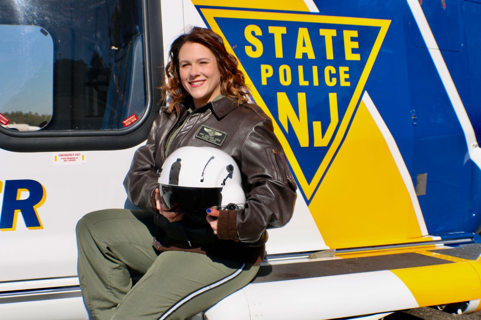 A woman is sitting on the side of a state police helicopter
