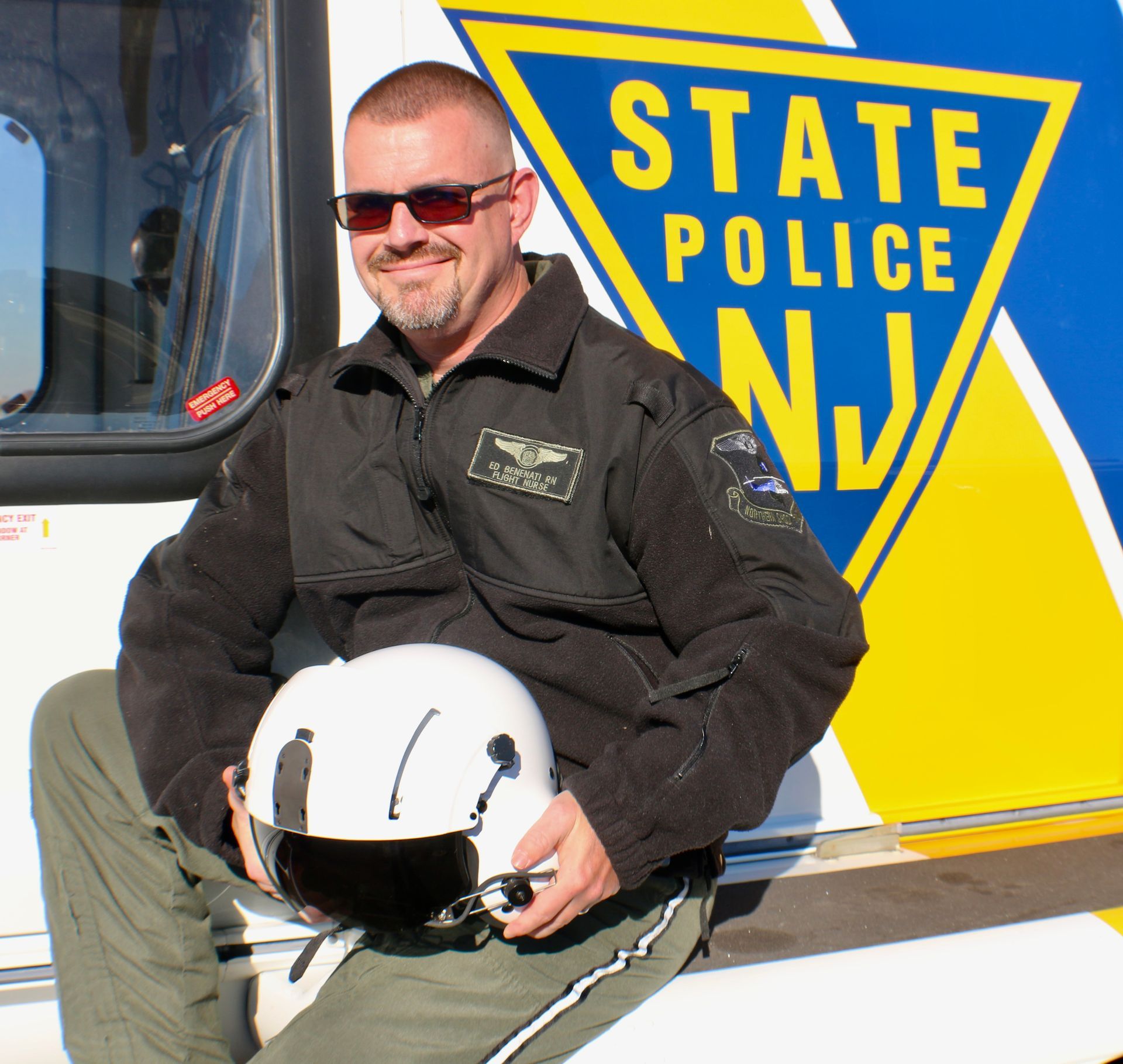 A man is sitting in front of a state police sign