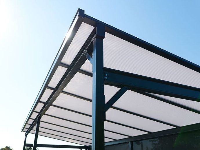 Modern metal canopy with translucent roof panels against a blue sky