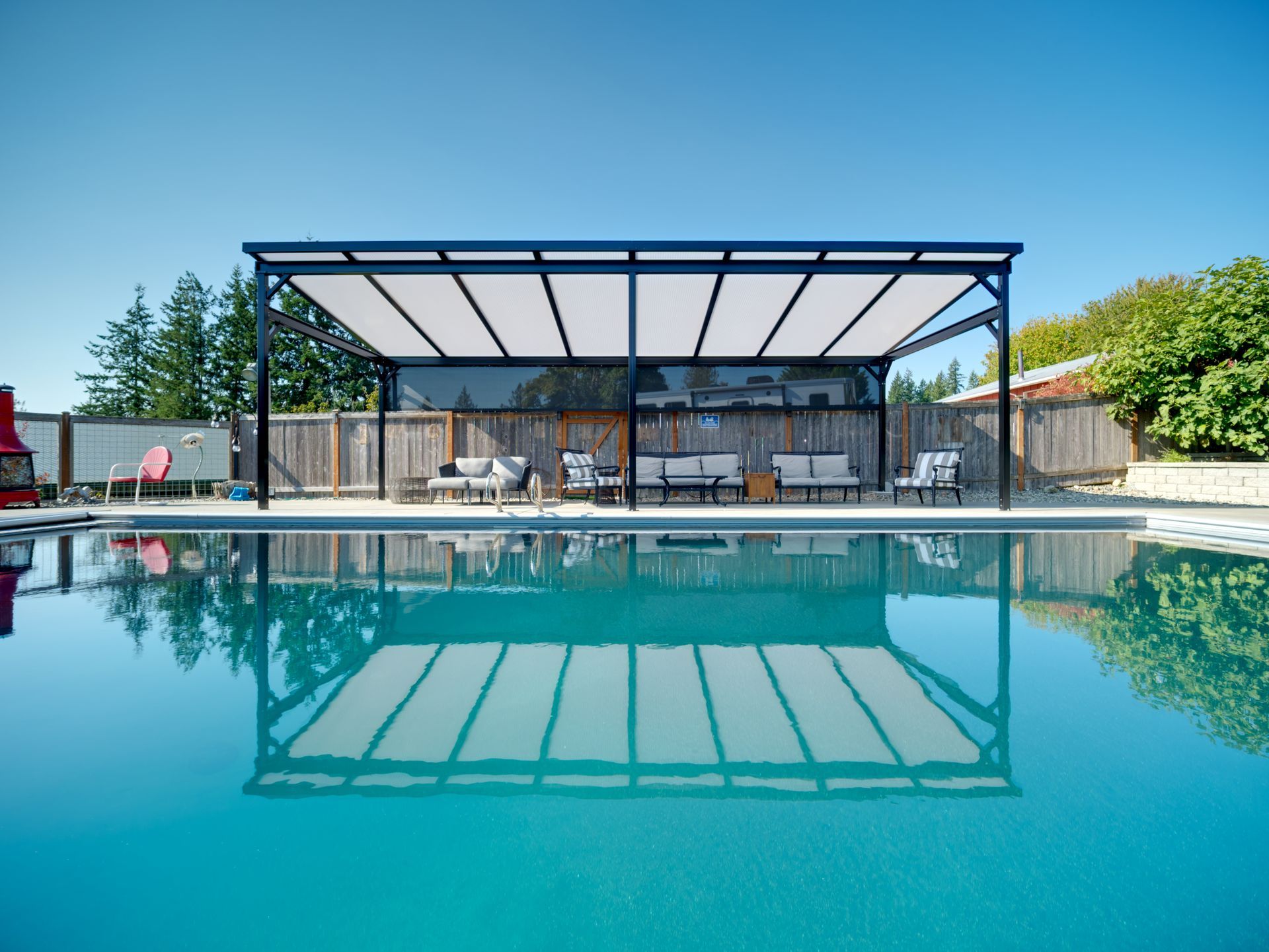 Backyard pool with a freestanding cover under a clear sky
