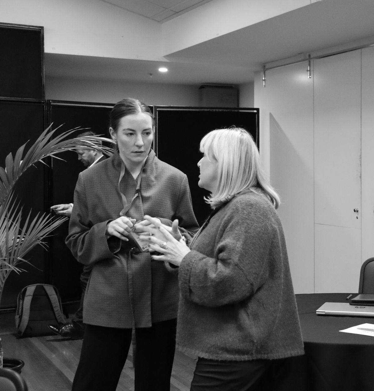 People chatting in a conference room near a table with papers and cups