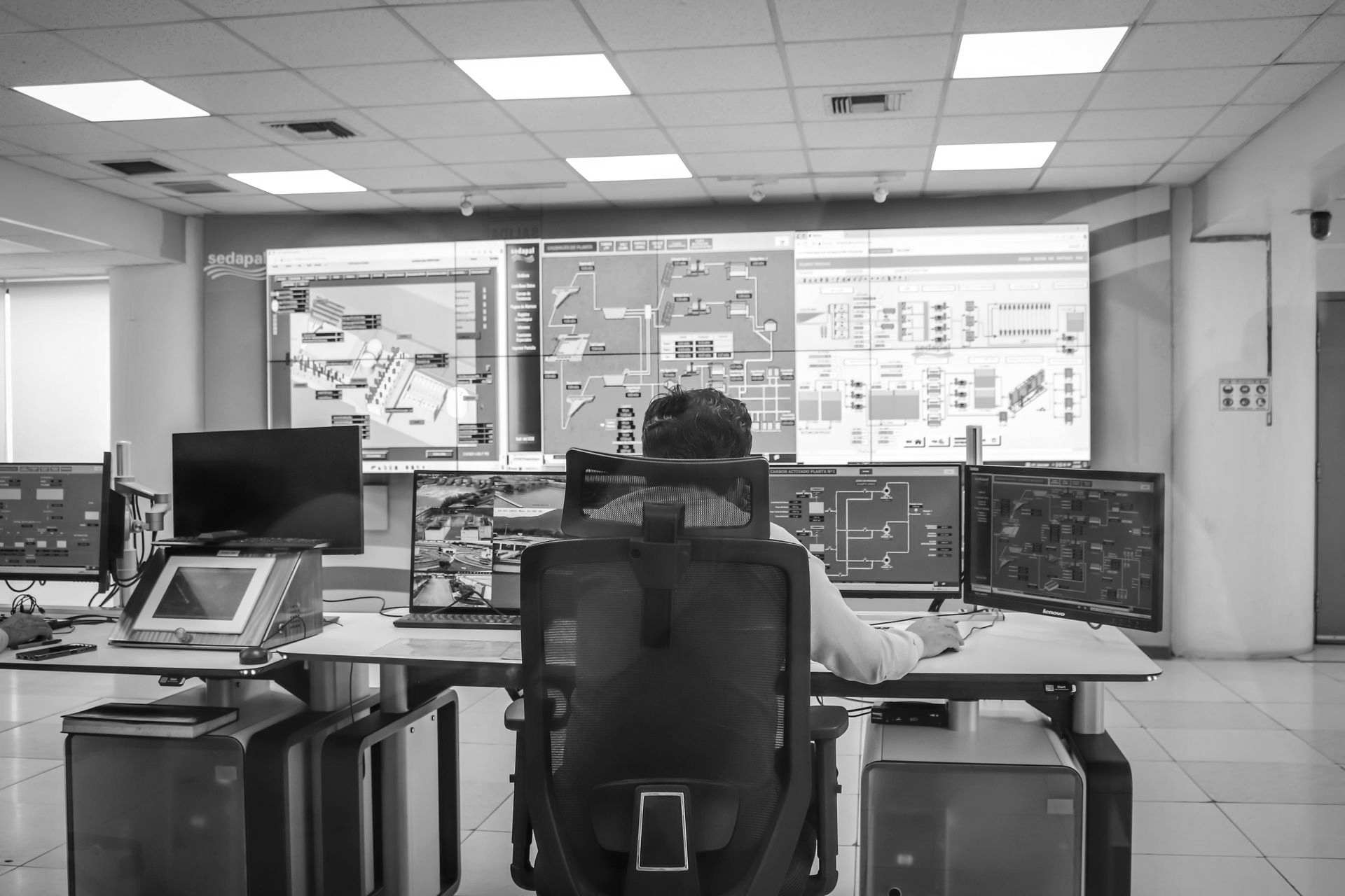 Person at a control desk with multiple monitors in a bright operations room