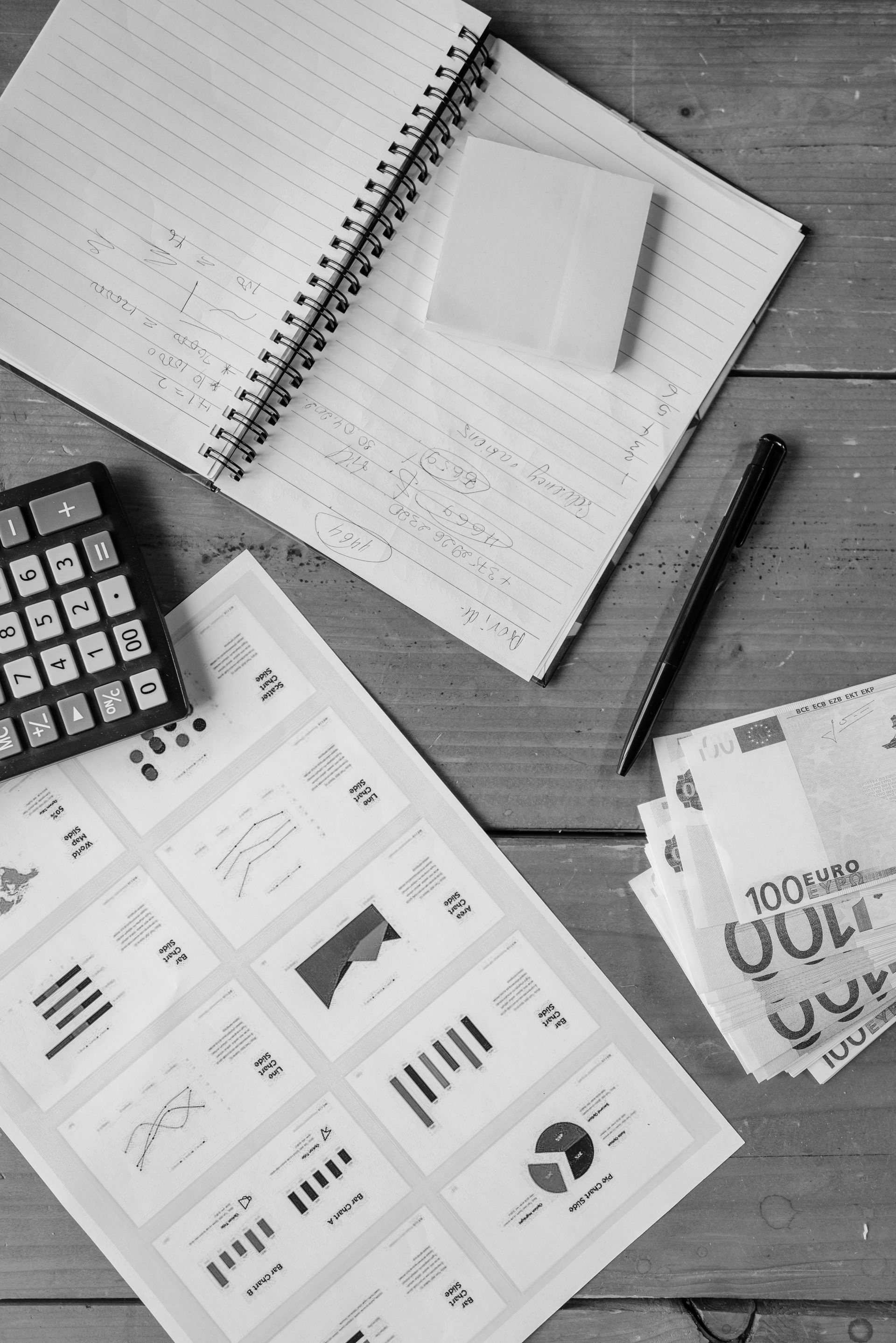 Overhead view of a desk with planner, notebook, calculator, pen, and paperwork