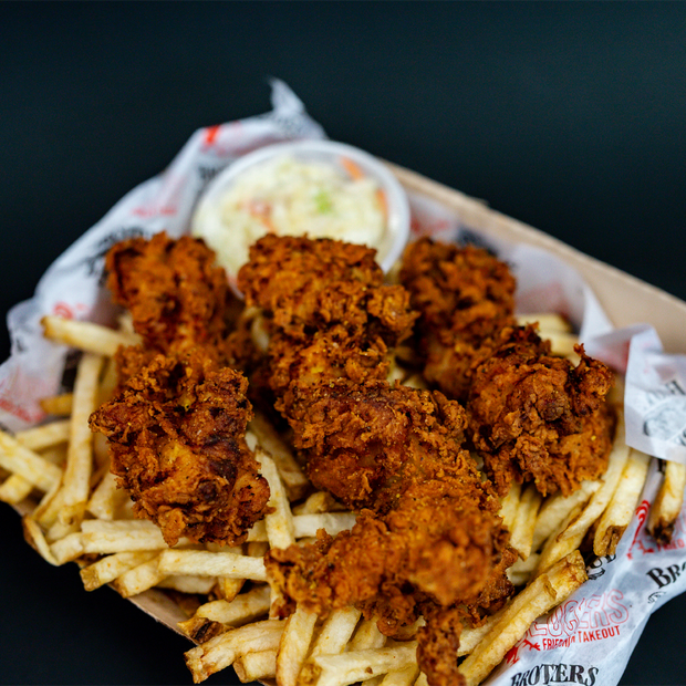 Chicken tenders on a bed of french fries.