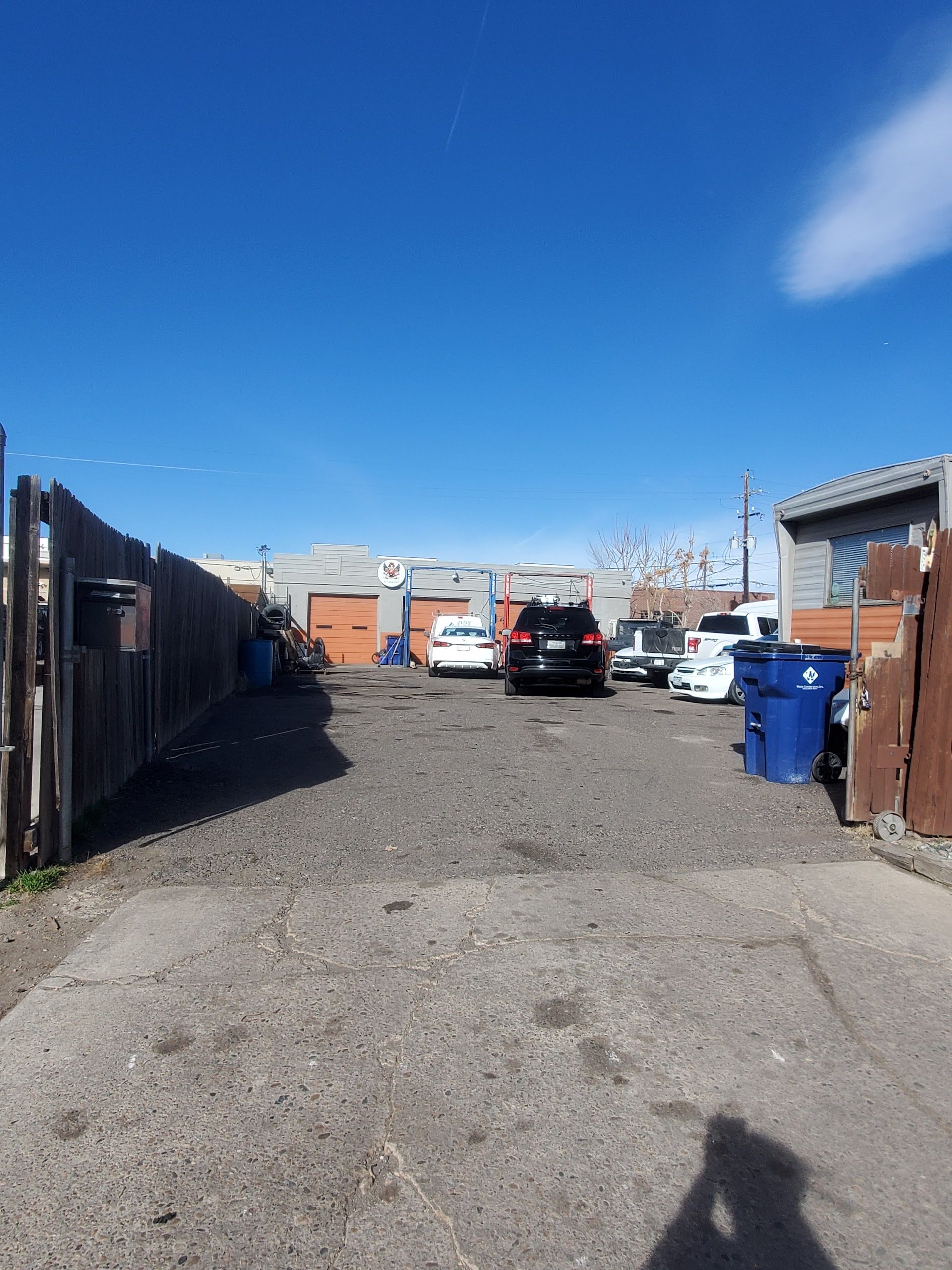 An alleyway with parked cars, garages, and a blue sky | Freebird Automotive