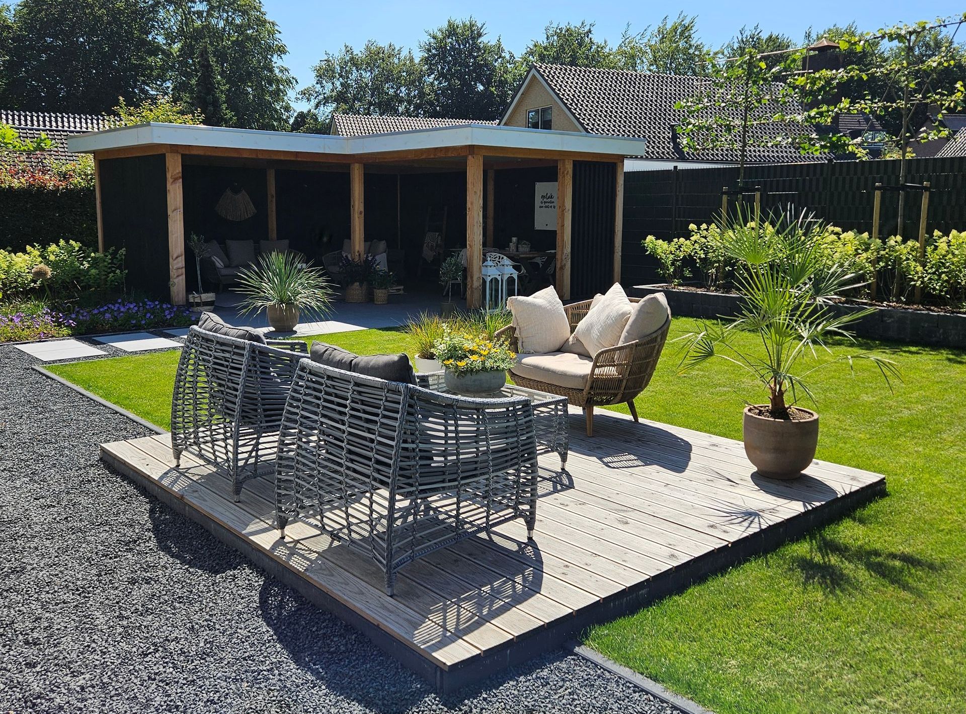 Achtertuin met groot gazon en met terras en overkapping.
