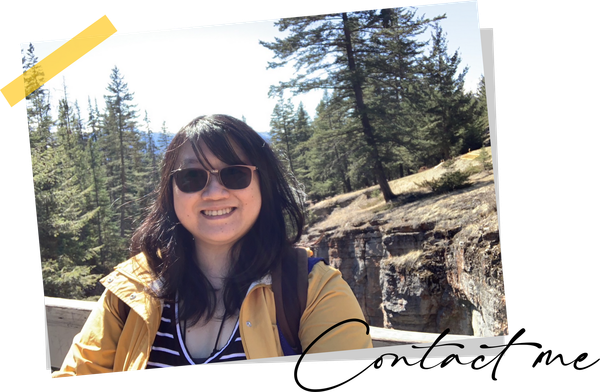 Woman smiling outdoors in sunglasses and a yellow jacket, with evergreen trees and cliffs behind her; “Contact Me” text overlay