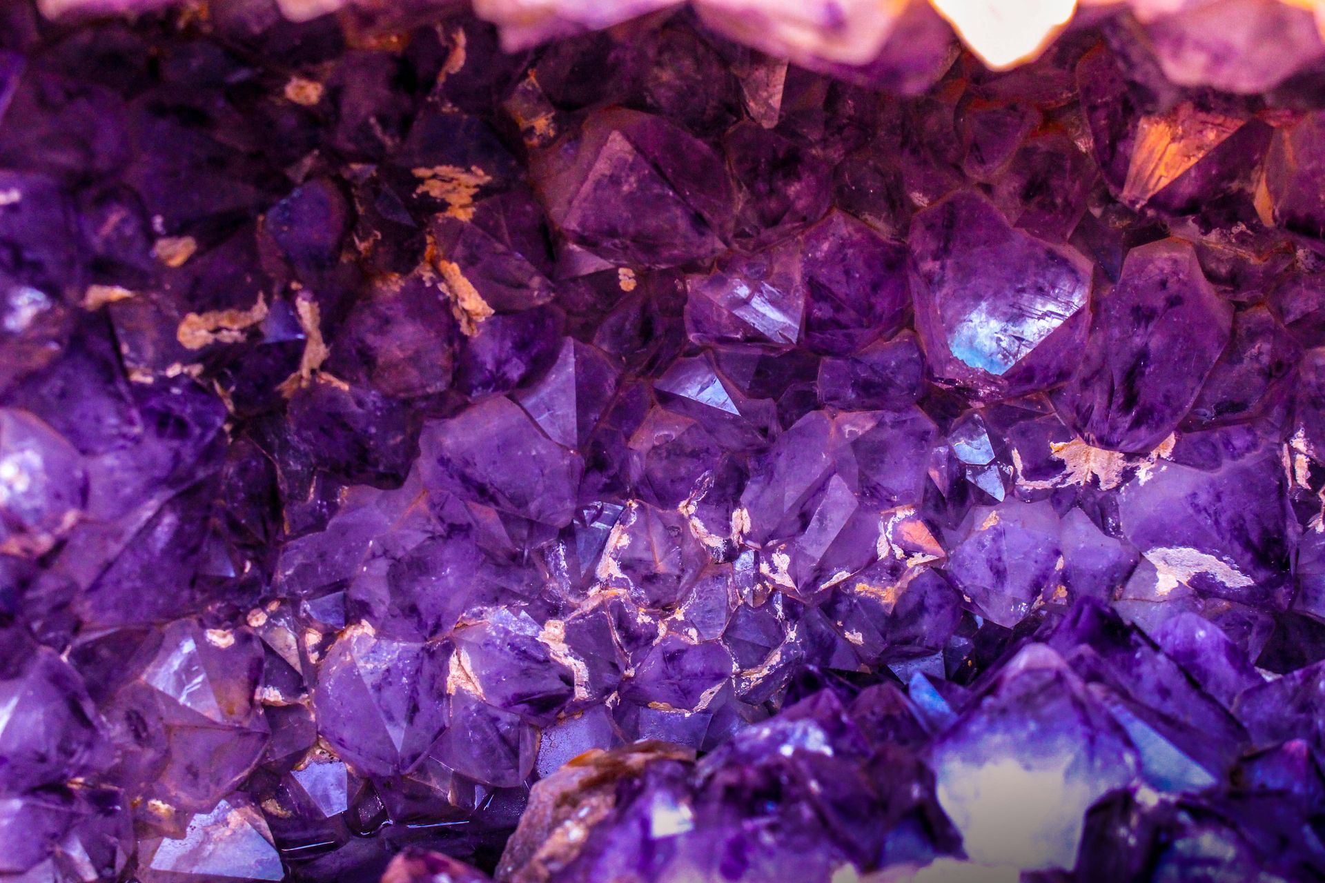 Close-up of shimmering purple crystals with faceted textures and pink highlights.