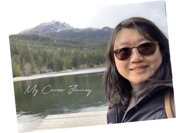 Woman in sunglasses smiling by a lake with forested mountains and snow in the background