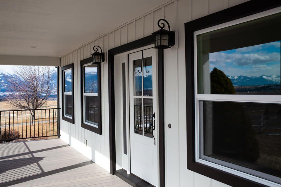 White house porch with dark trim, windows, and mountain view.