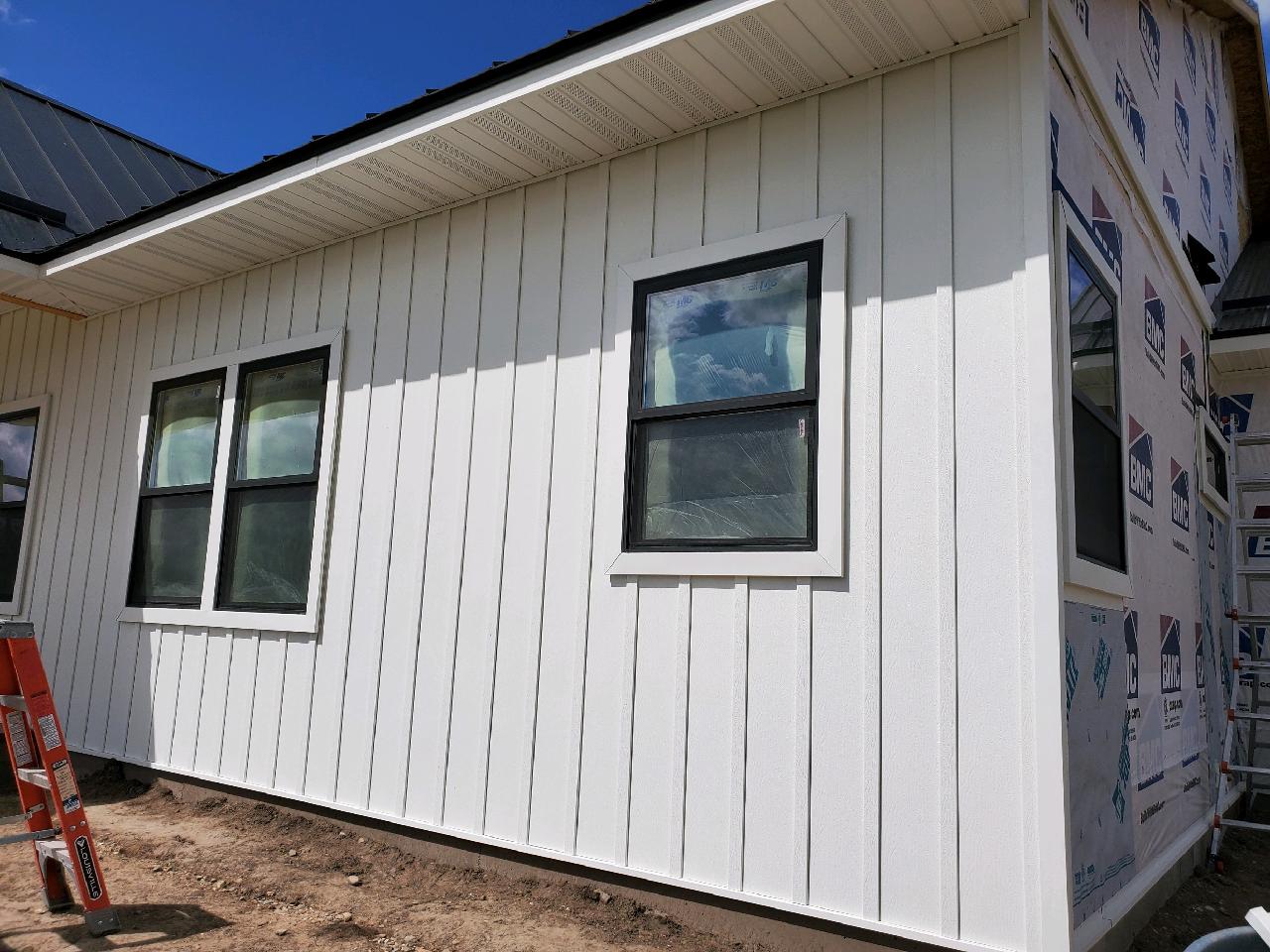 Exterior of a building with white siding, black-framed windows, and a dark roof.