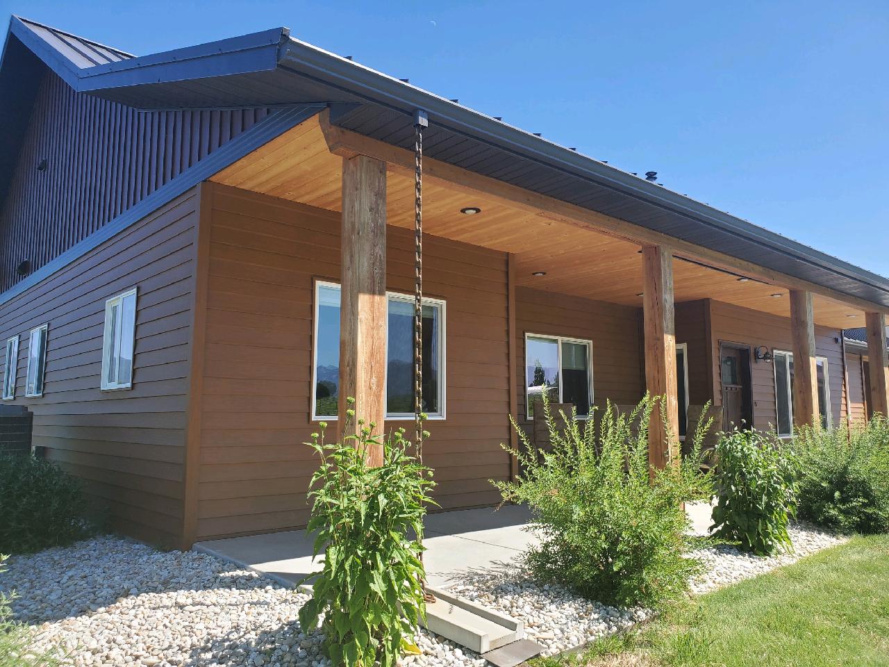 Brown building with covered porch and wooden posts; a rain chain hangs.
