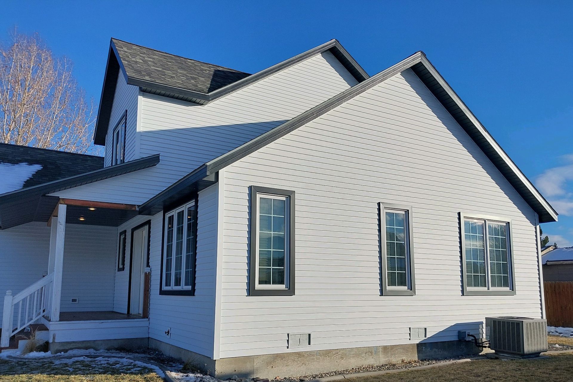 White two-story house with black trim, gray roof, and three windows on the right side.