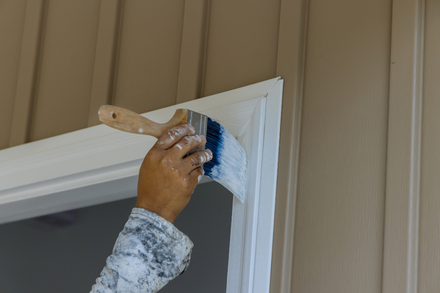 Painter applying white paint to interior door trim