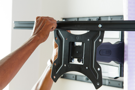 Technician installing an adjustable wall mount bracket for a television