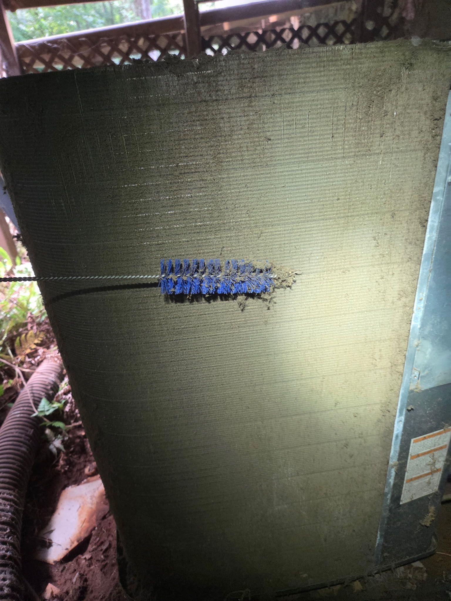 Large green textured panel with a small blue label in the center, outdoors near rocks and foliage.
