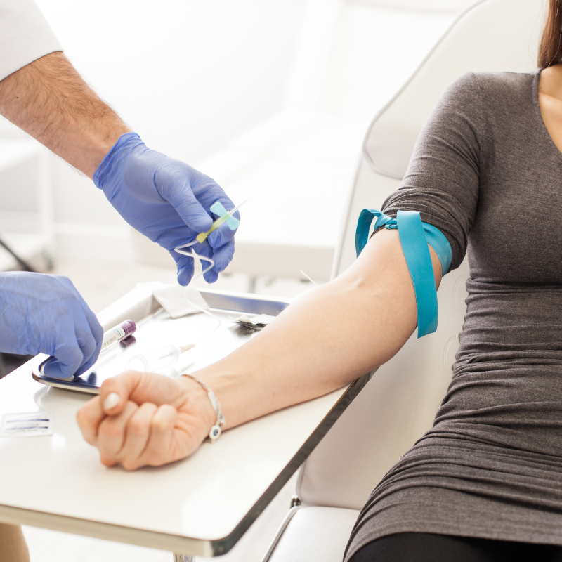 Healthcare worker drawing blood from a seated patient’s arm in a clinic