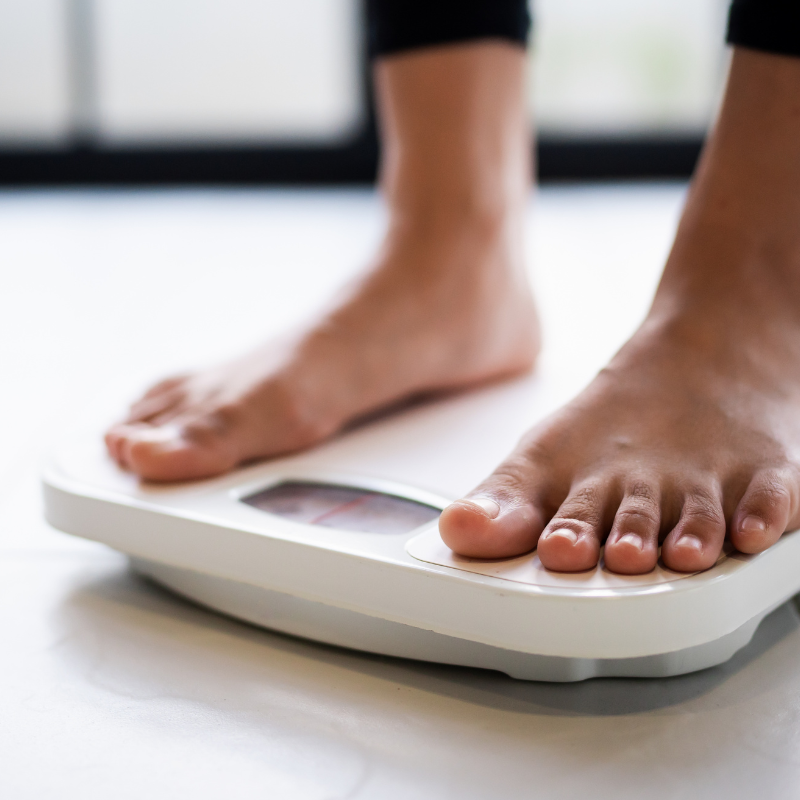 Feet standing on a white bathroom scale with a digital display.