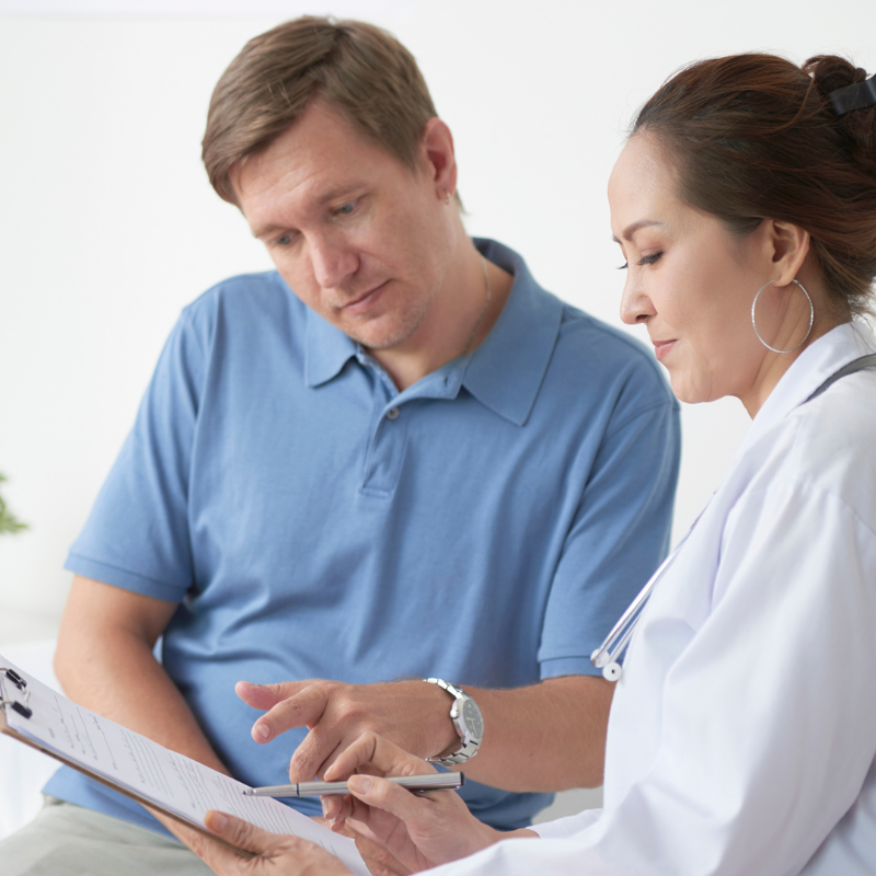 Two people reviewing a clipboard together, with one pointing at the document in a bright office.
