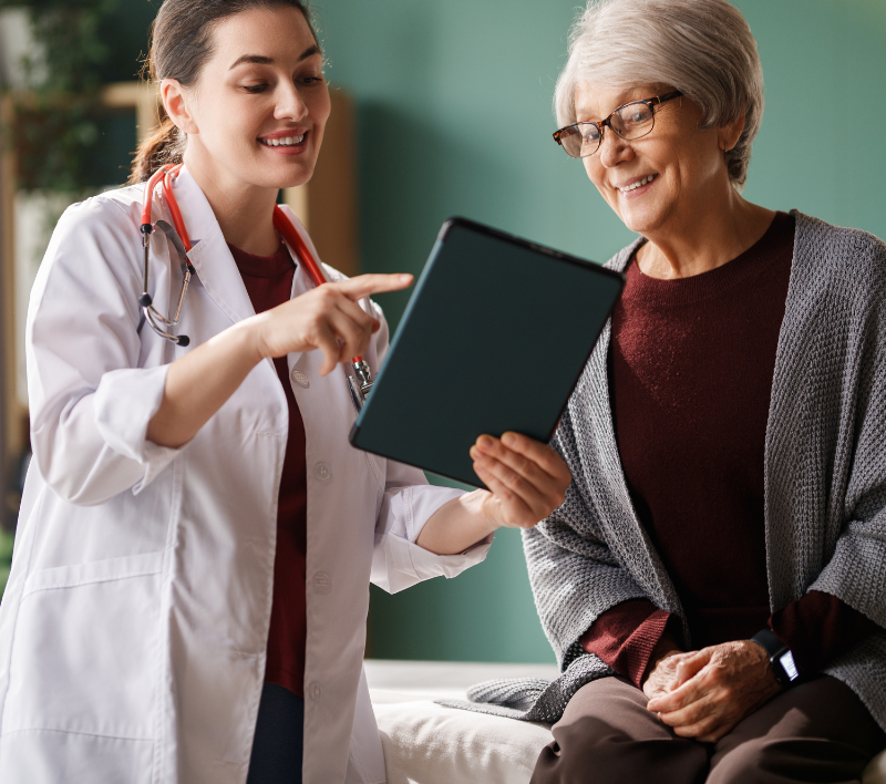 Doctor showing a tablet to an older woman in a bright clinic room
