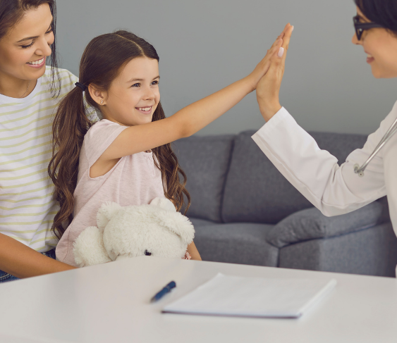 Child high-fiving a doctor while a smiling adult sits nearby in a clinic waiting area