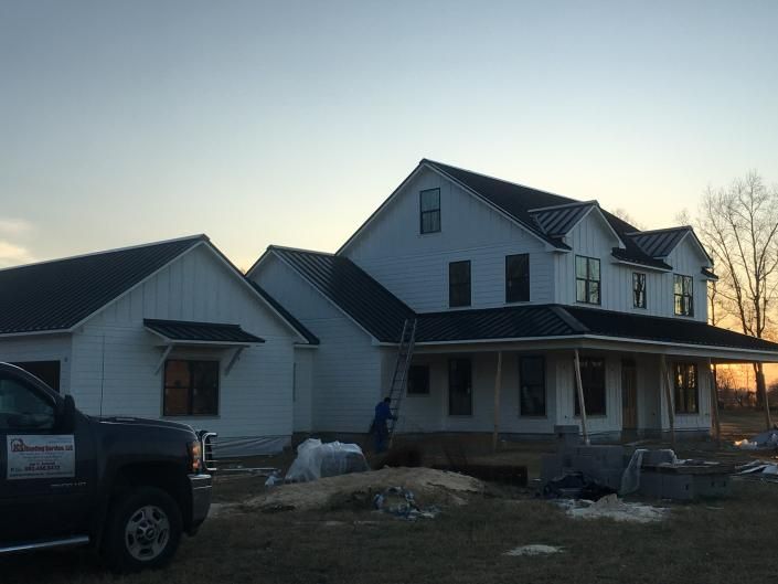 Two-story white house with porch and parked truck at dusk, with patches of snow in the yard