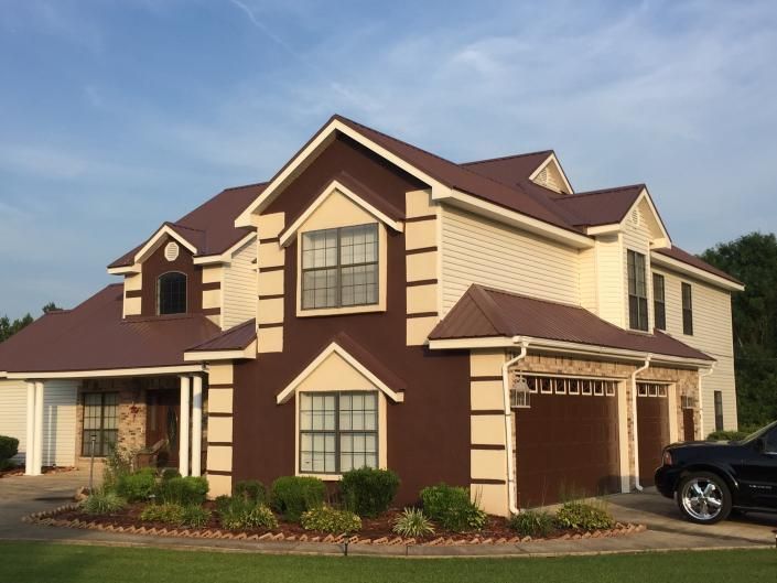 Suburban two-story beige and brown house with a dark roof and a parked car in the driveway