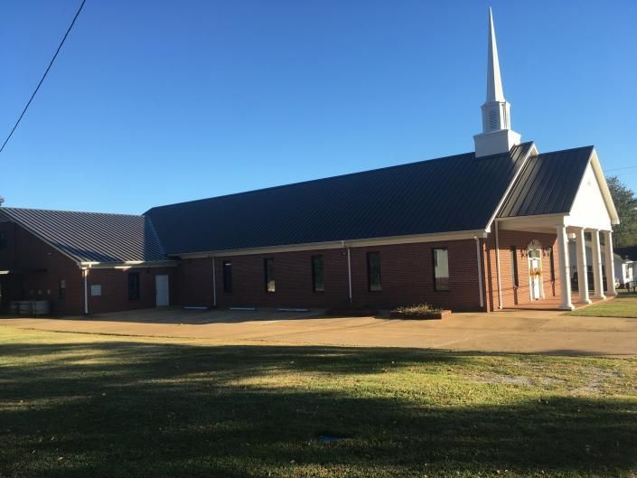 Brick church building with a tall white steeple under a clear blue sky