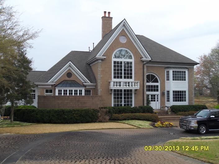 Brick suburban house with large arched windows and a parked car in the driveway