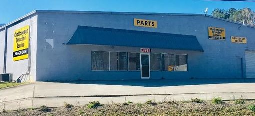 Blue storefront with a black awning, a “PARTS” sign, and windows along the front