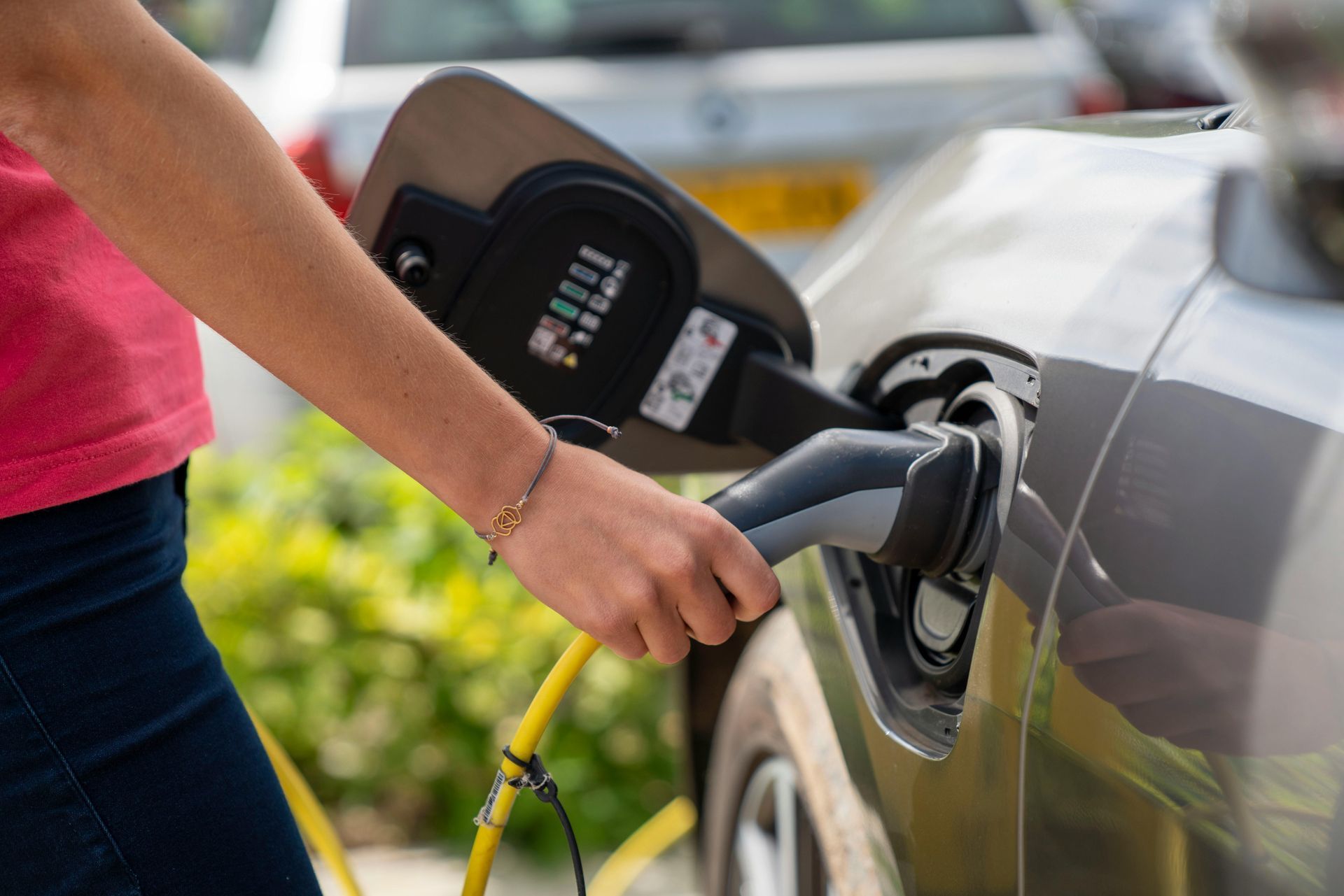 A circular Ampol AmpCharge electric vehicle wall charger mounted on a textured grey concrete wall.