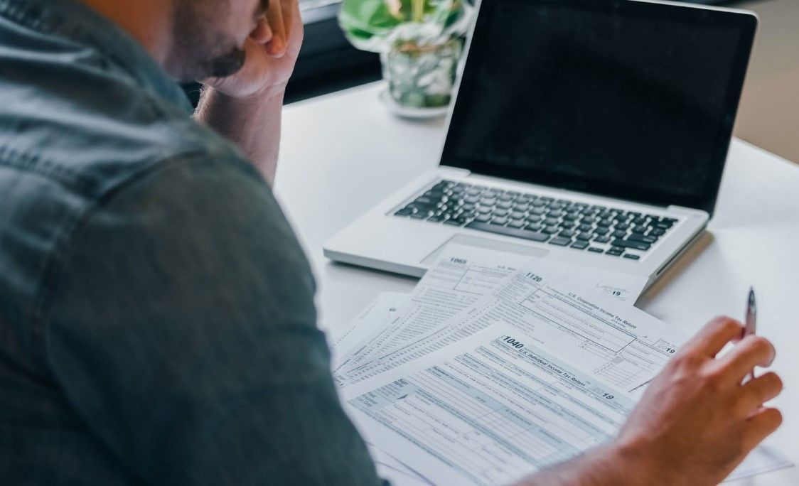 a man is sitting at a table with a laptop and papers