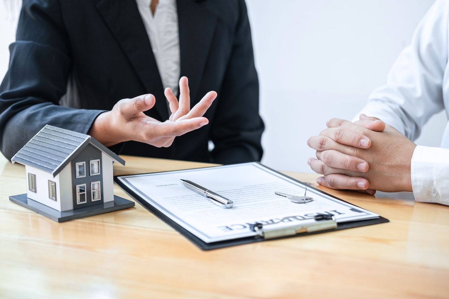 A woman is sitting at a table talking to a man about buying a house.