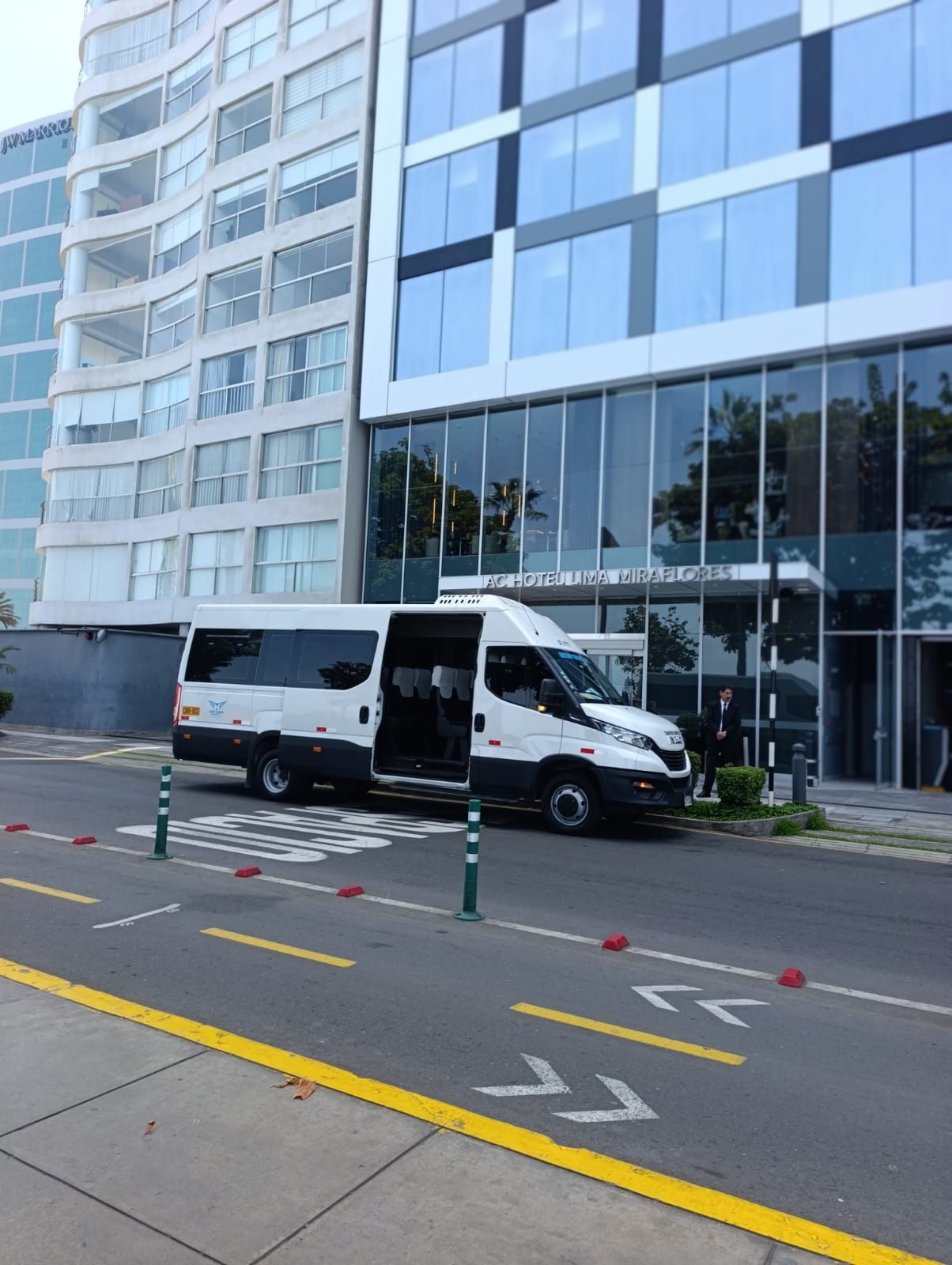 Furgoneta de carga blanca aparcada junto a un moderno edificio de oficinas de cristal en una calle de la ciudad.