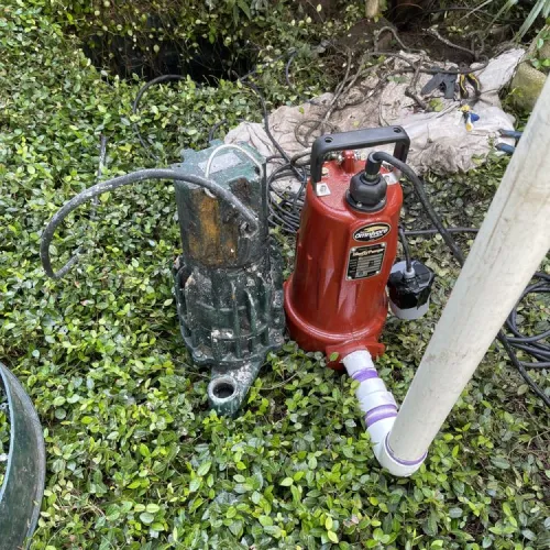 A red water pump is sitting on top of a lush green hedge | The Duke Of Plumbing