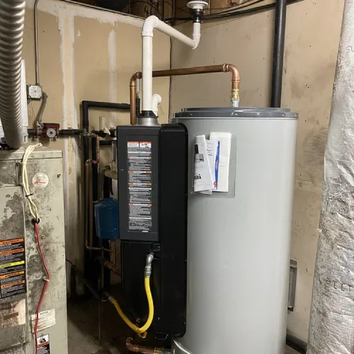 A water heater is sitting next to a furnace in a basement | The Duke Of Plumbing