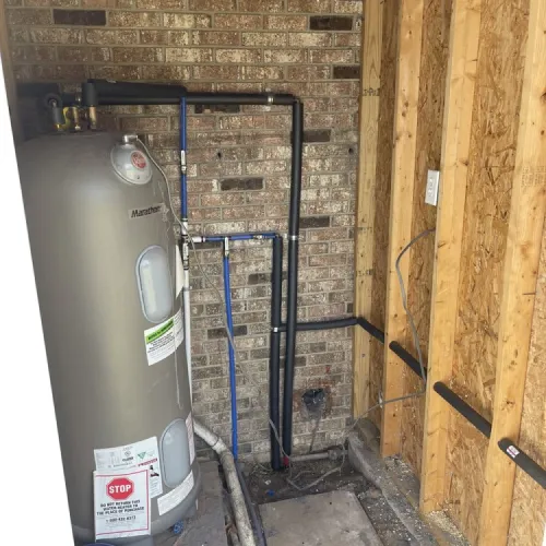A water heater is sitting in a room next to a brick wall | The Duke Of Plumbing