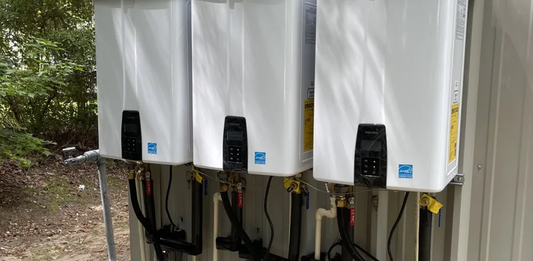 A row of white water heaters sitting next to each other on a wall | The Duke Of Plumbing