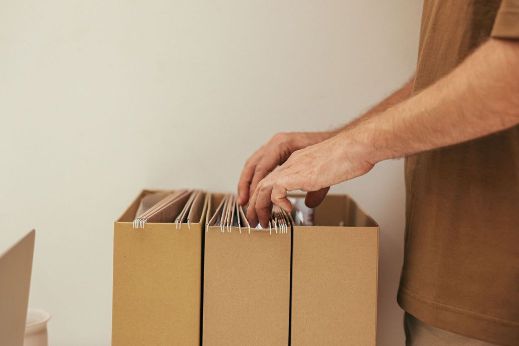 Hands sorting records in a cardboard box on a table
