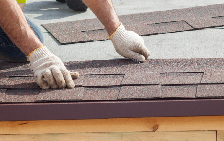 a man is installing shingles on a roof .