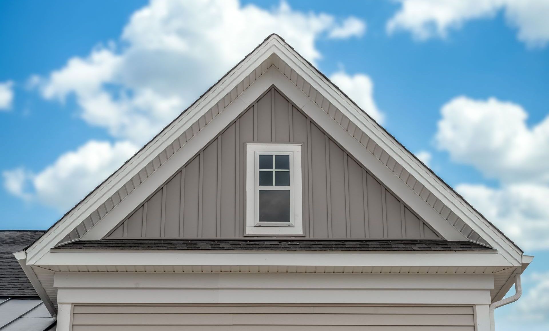 the roof of a house with a window and a blue sky in the background .