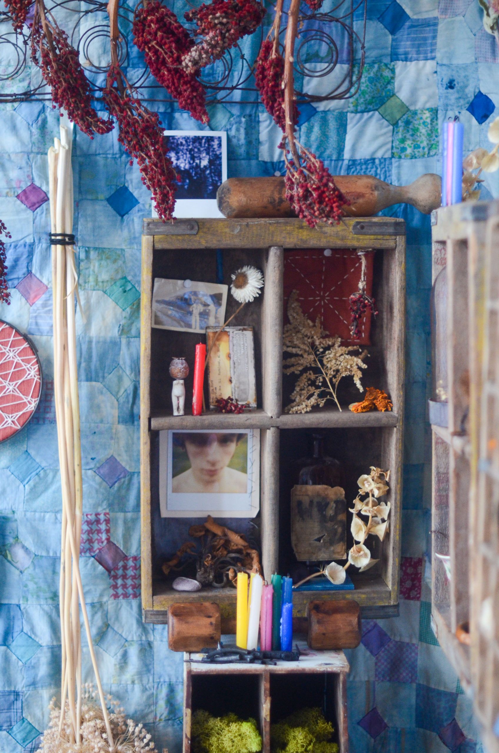 Colorful wall-mounted shelf with assorted small objects, bottles, and decorative items against a blue patterned background